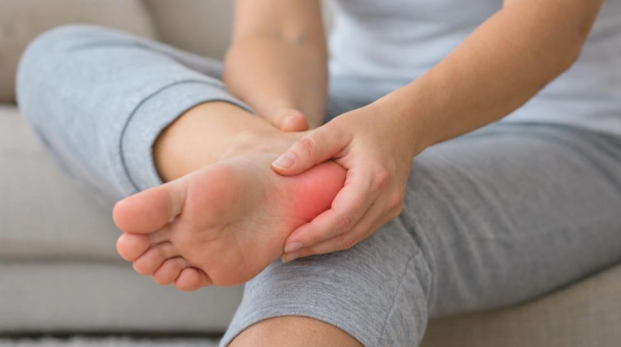 Heel spur pain shown with person holding heel